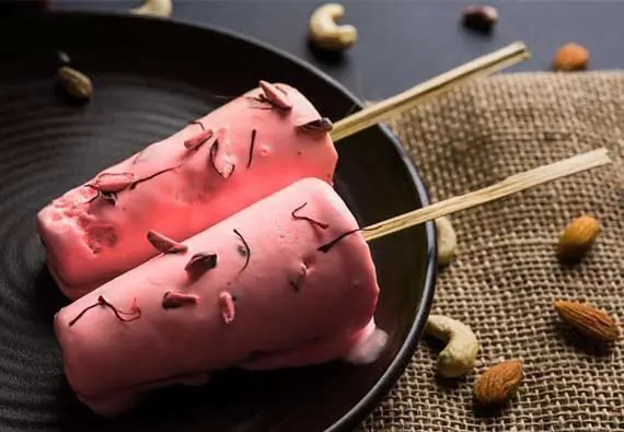 Two pink ice cream sticks on a black plate.