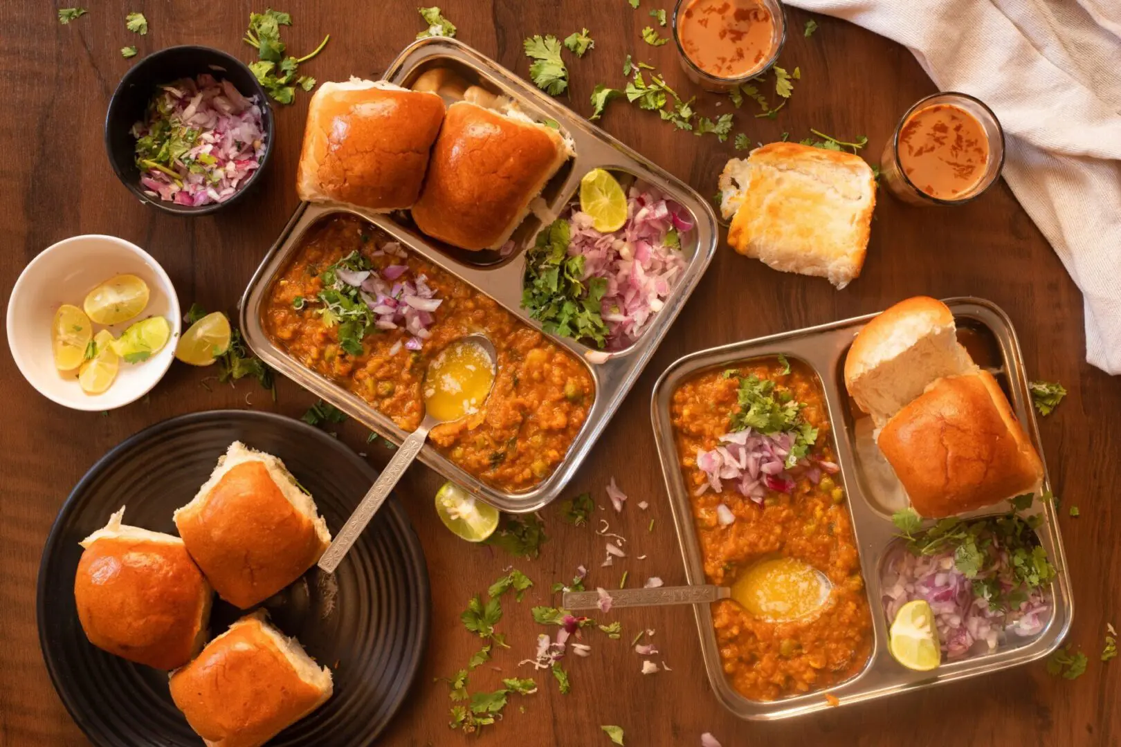 A table with plates of food and buns on it.