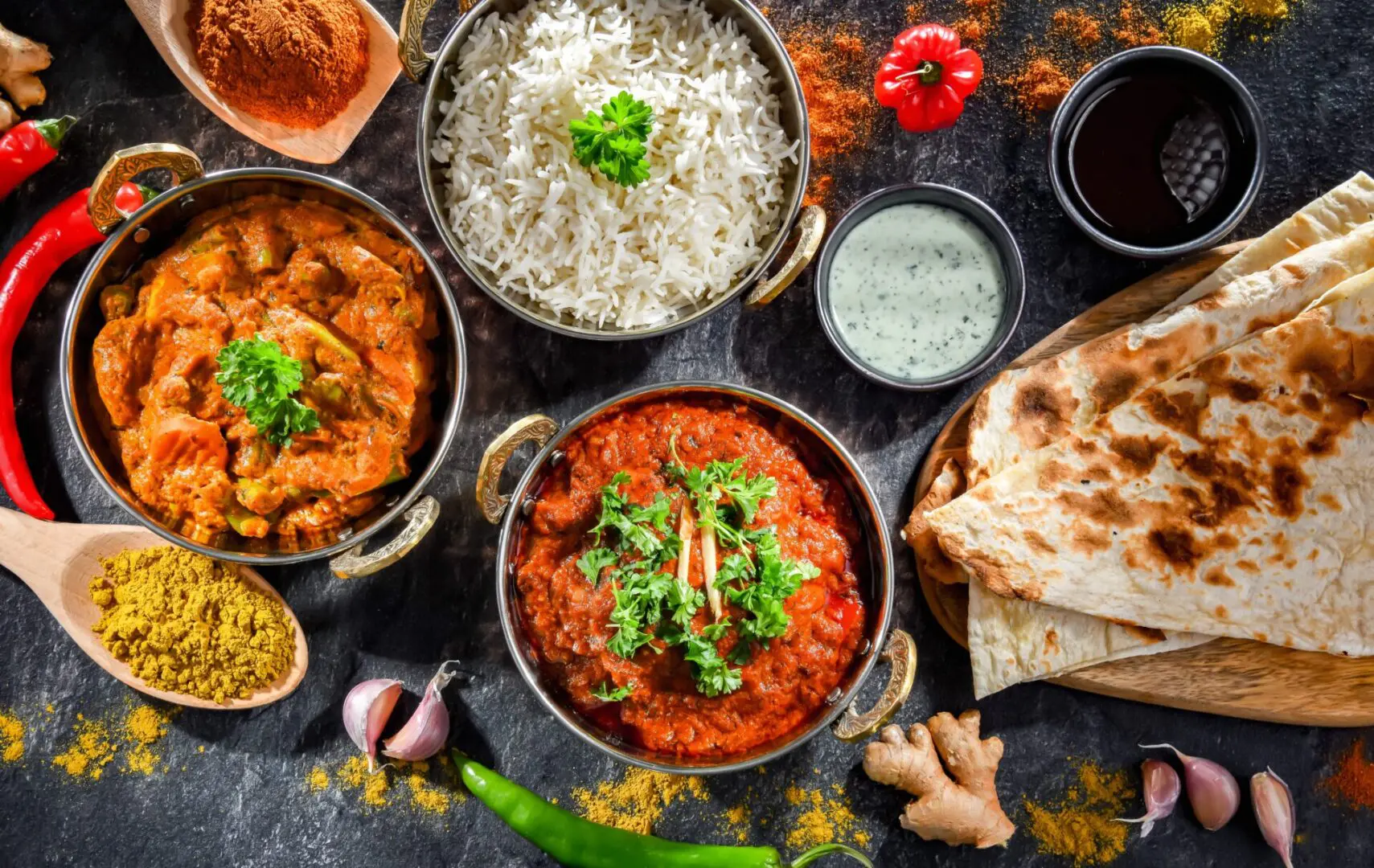 A table topped with bowls of food and sauces.